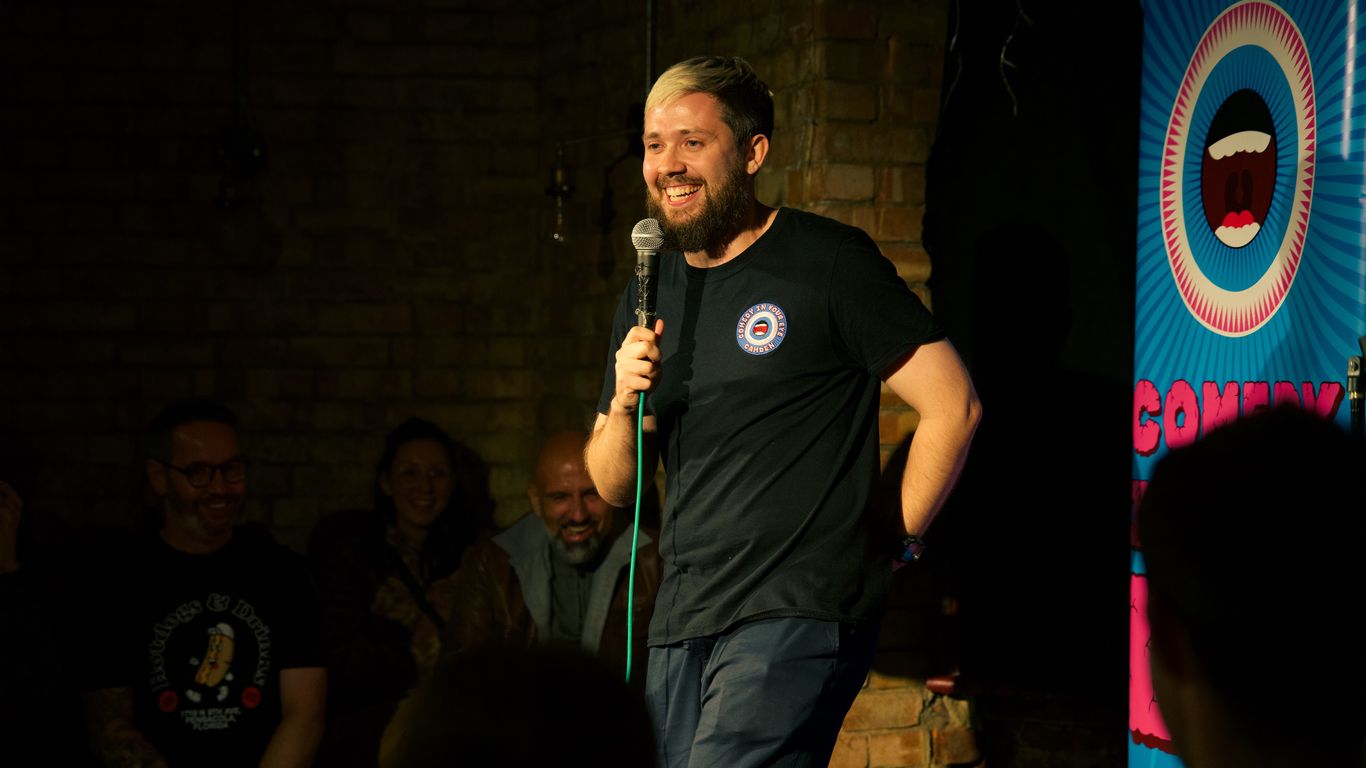 A man with a microphone performs on stage in front of an audience.