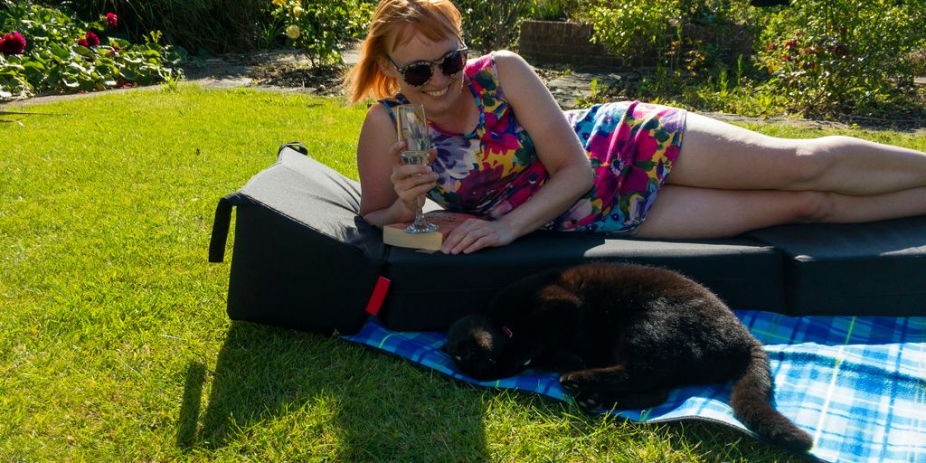 a person lying on a blanket with a cat on the lap