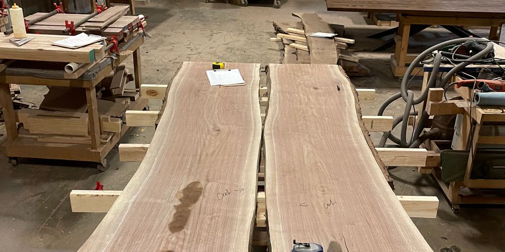 Woodworking shop with large wooden slabs on worktables.