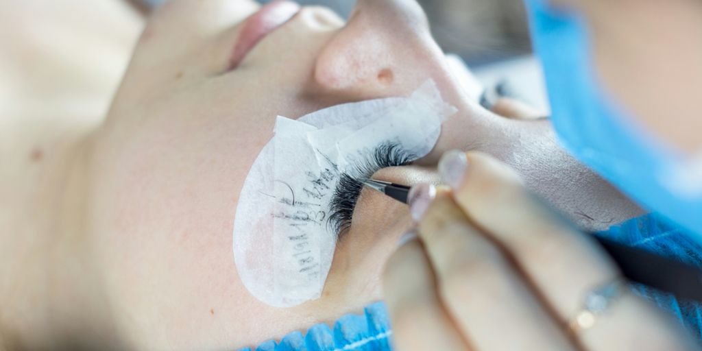 a woman getting her eyelashes done by a professional makeup artist