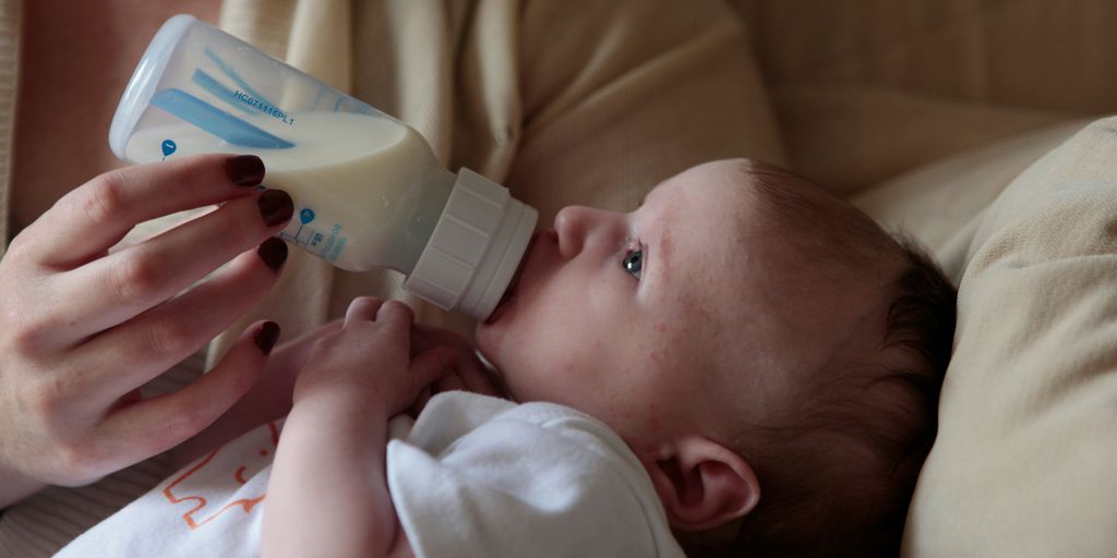 a woman feeding a baby with a bottle of milk