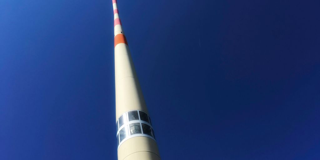 a tall white tower with a red and white stripe on it