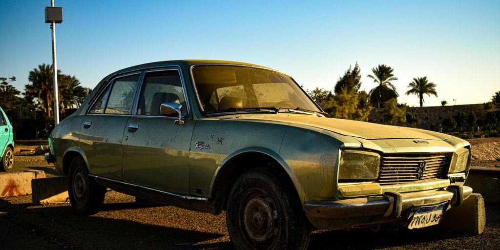 an old car is parked next to a green car