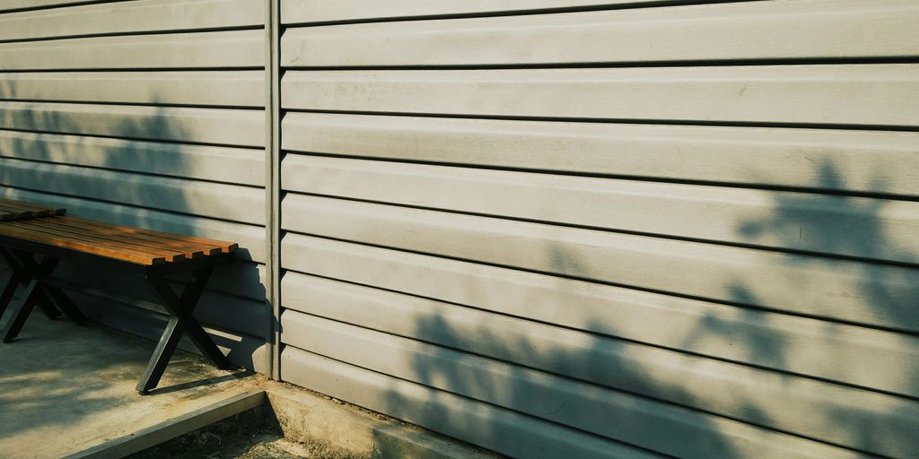 a wooden bench sitting next to a white wall