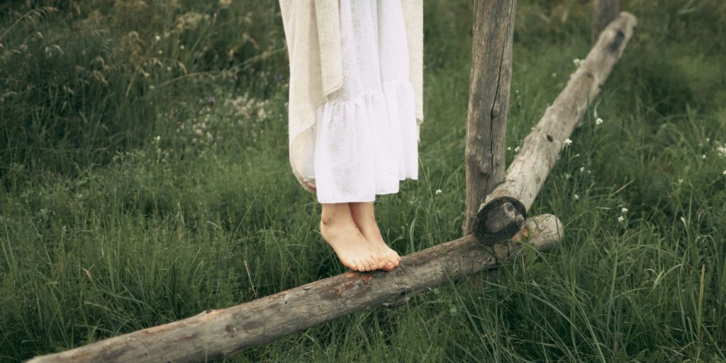 a woman in a white dress standing on a wooden fence