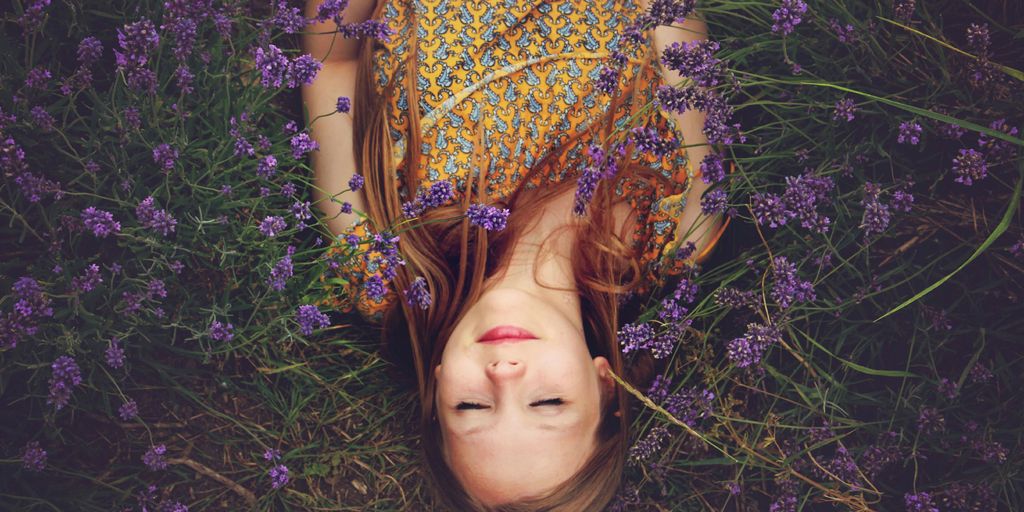 woman in yellow and teal top sleeping beside lavenders