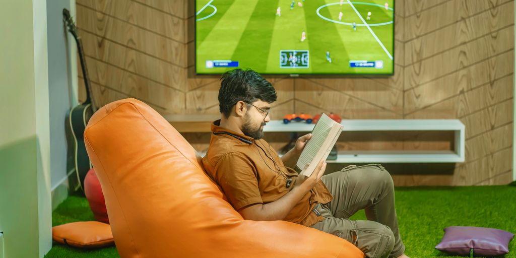 a man sitting on a bean bag chair reading a book