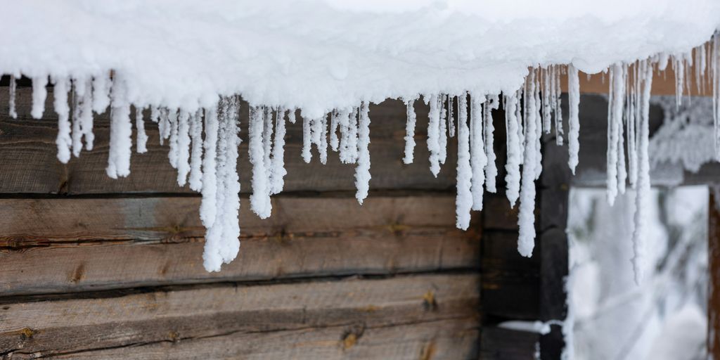 icicles are hanging from the roof of a cabin