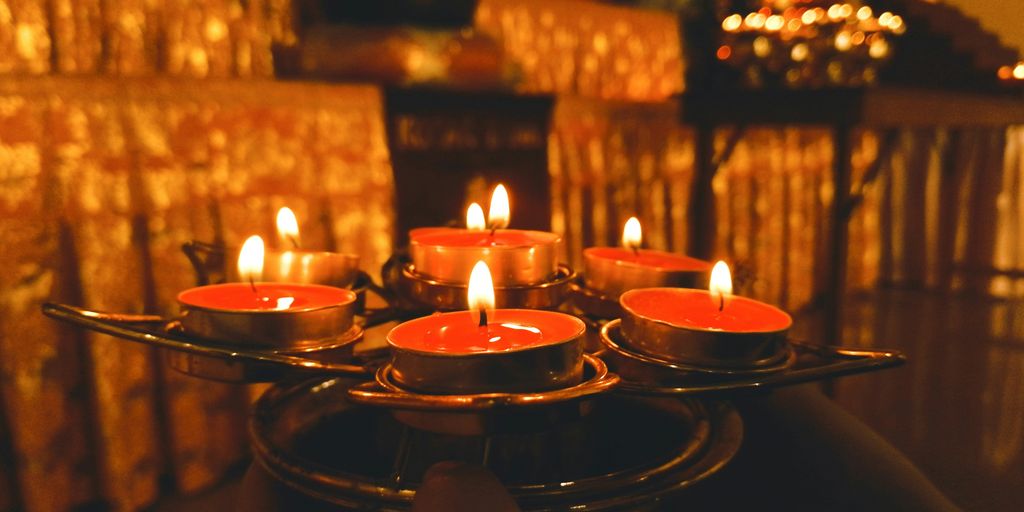 a person holding a tray of lit candles
