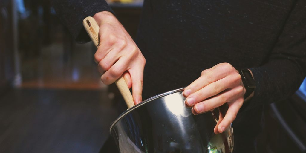 a person stirring a pot with a wooden spoon