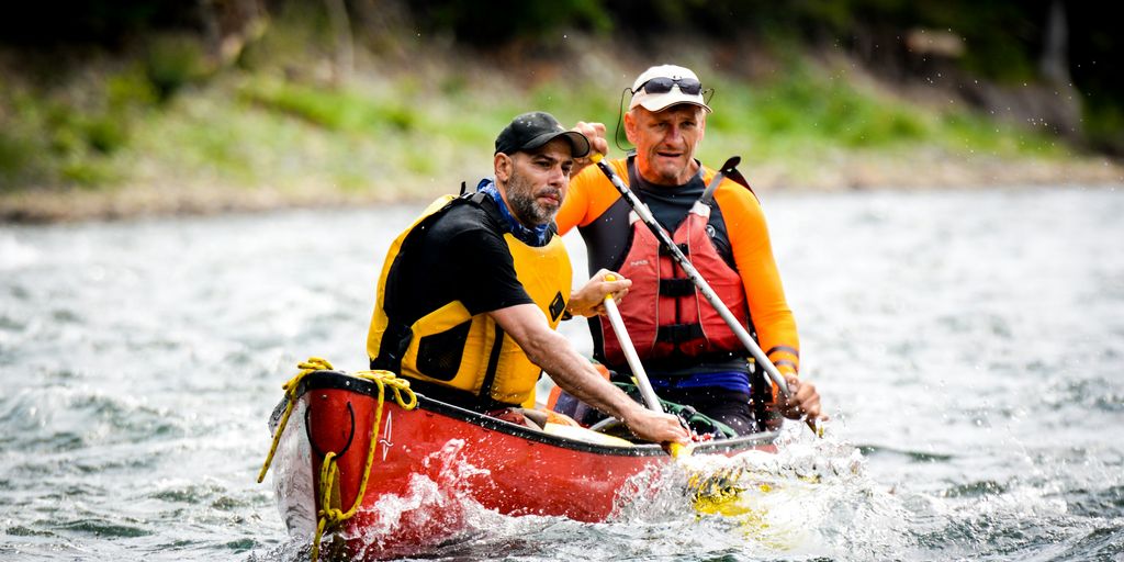 two men riding on red canoe boat