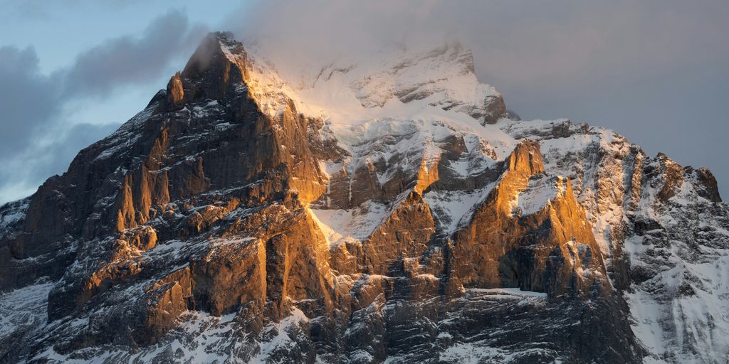 a mountain covered in snow with a sky background