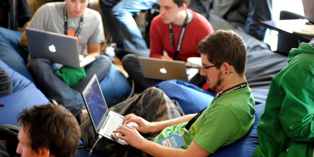 man sitting on blue bean bag usinglaptop