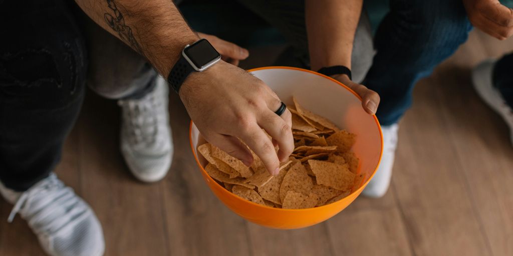 person holding orange bowl with potato chips