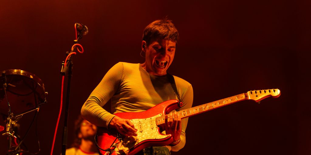 A man playing a guitar in front of a microphone