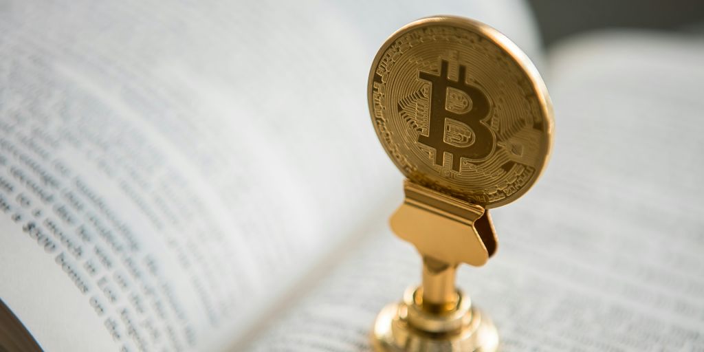 bitcoin on gold stand on top of book