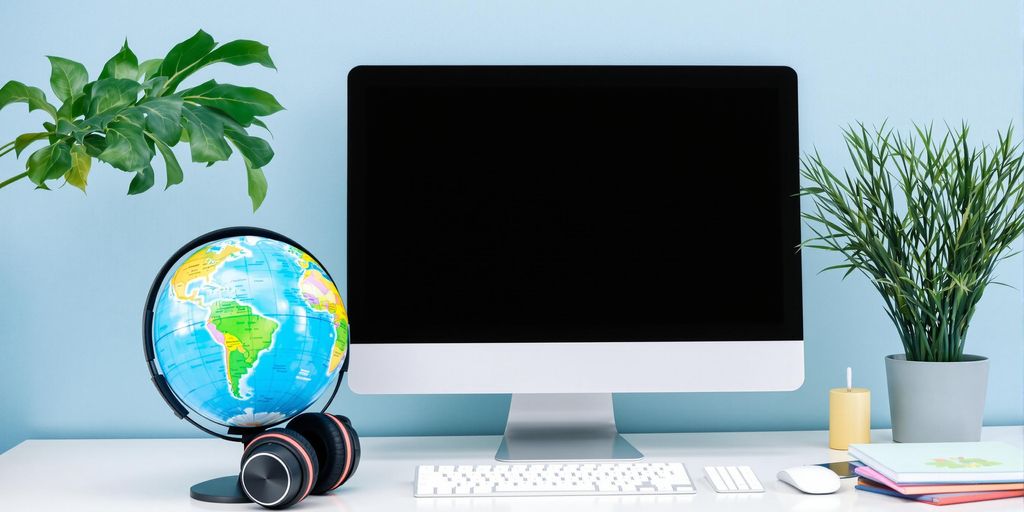 Workspace with computer, headphones, and globe for translation.
