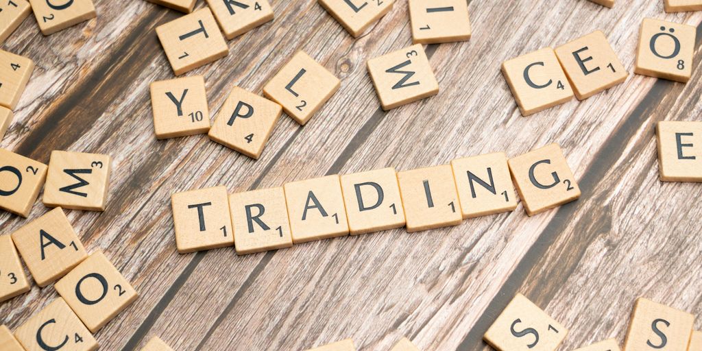 scrabble tiles spelling the word trading on a wooden surface