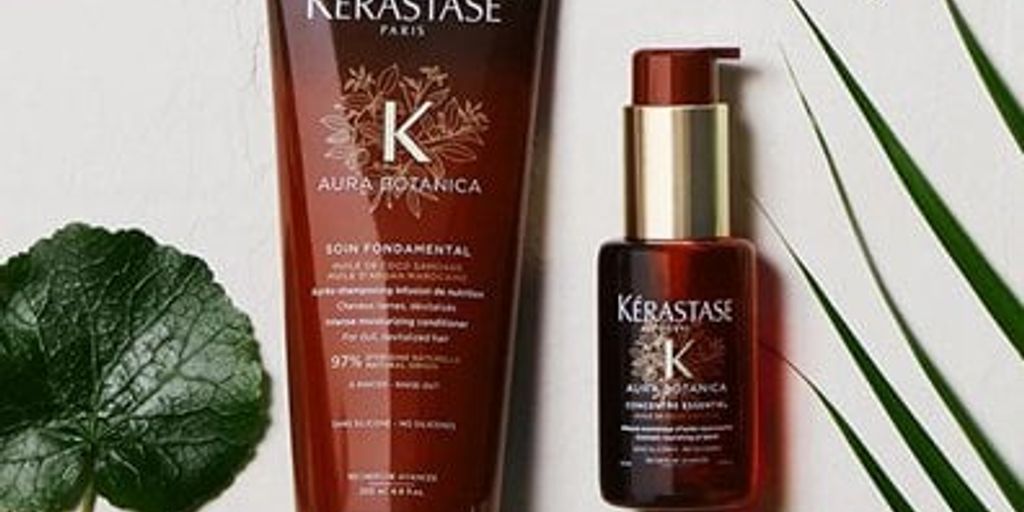 Kérastase haircare bottles with plant leaves on a neutral background.