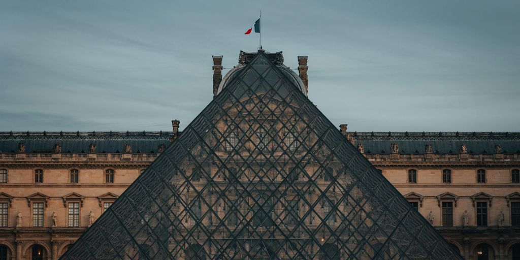 a very tall glass pyramid with a flag on top of it