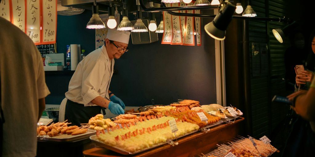 A chef prepares japanese food in a stall.