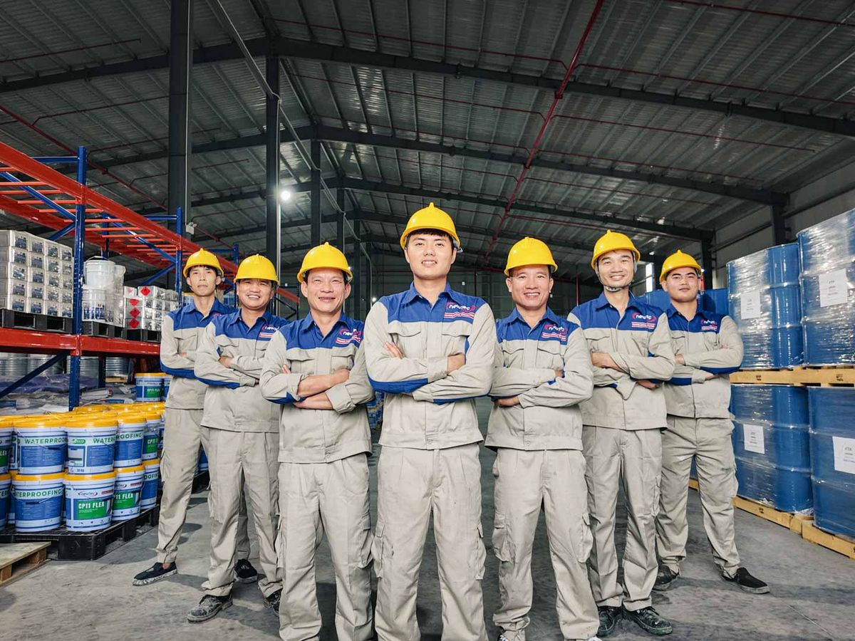 Group of workers in a warehouse, wearing safety gear and helmets.