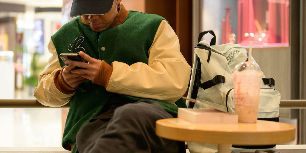 A man sitting on a bench looking at his cell phone