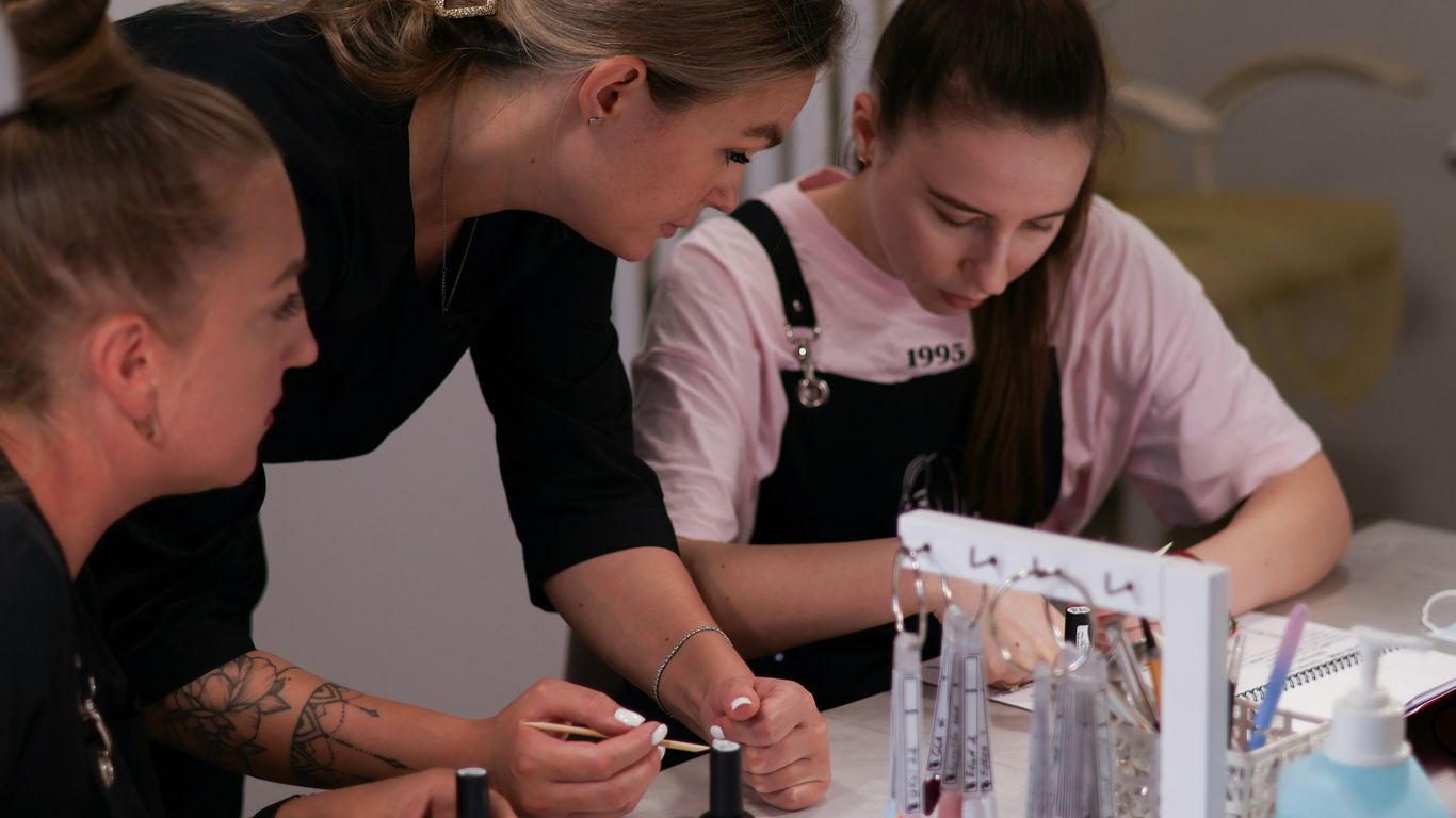 a group of women sitting around a table working on nail polish