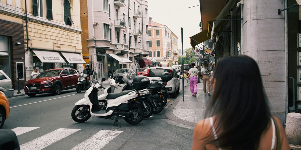 A woman walking down a street next to parked motorcycles