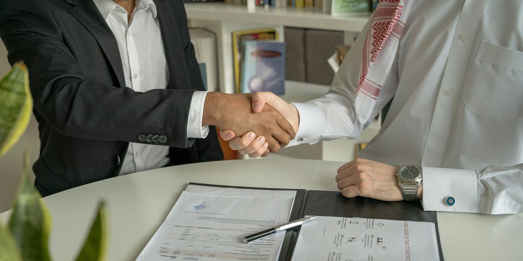 a couple of men shaking hands over a desk
