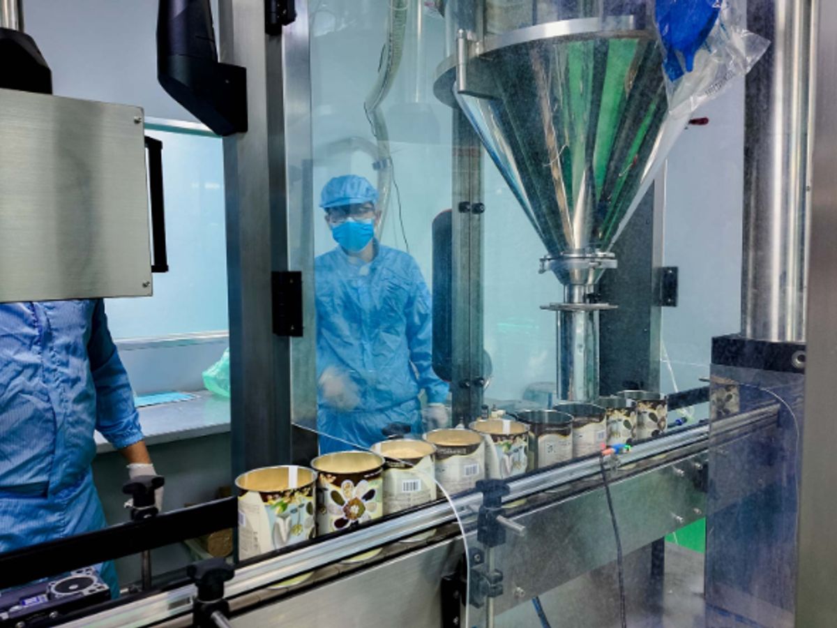 Manufacturing facility with workers and automated filling equipment.