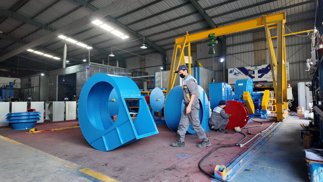 Industrial workshop with large blue machinery and workers present.