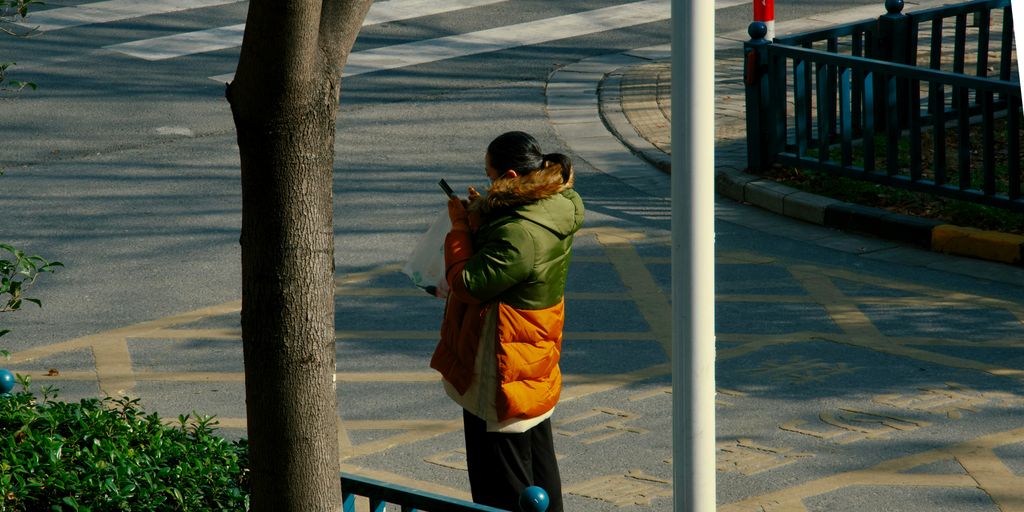 a woman standing on a street corner holding a cell phone