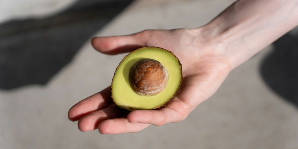 a person holding an avocado in their hand