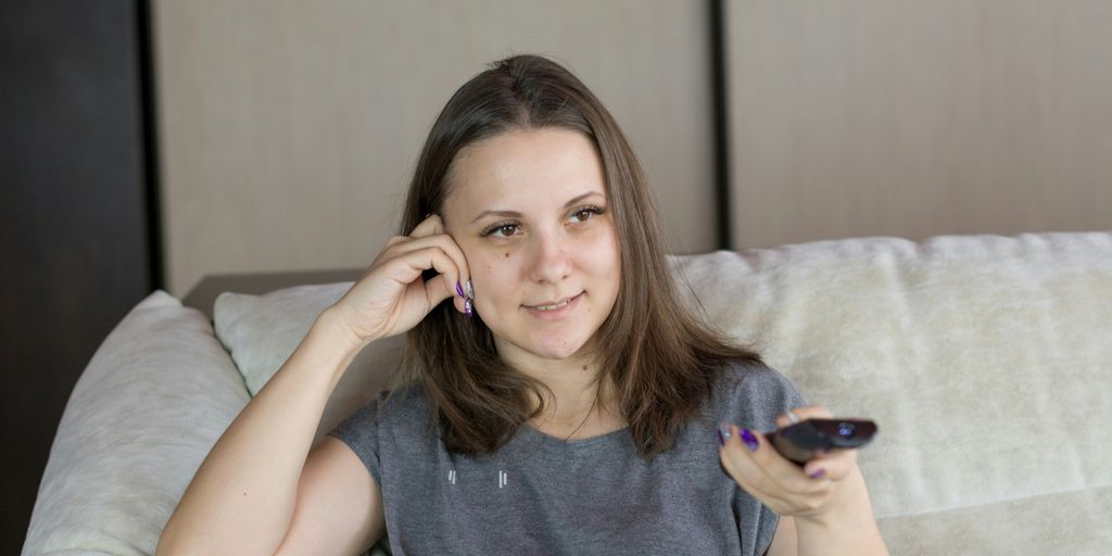 a woman sitting on a couch holding a remote control