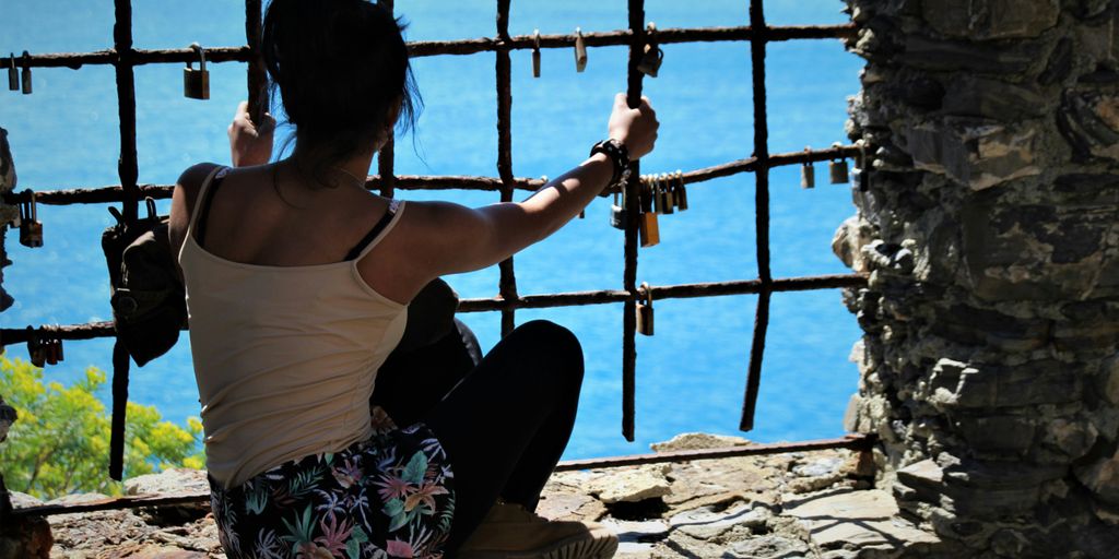 woman in brown tank top and black pants sitting on rock during daytime