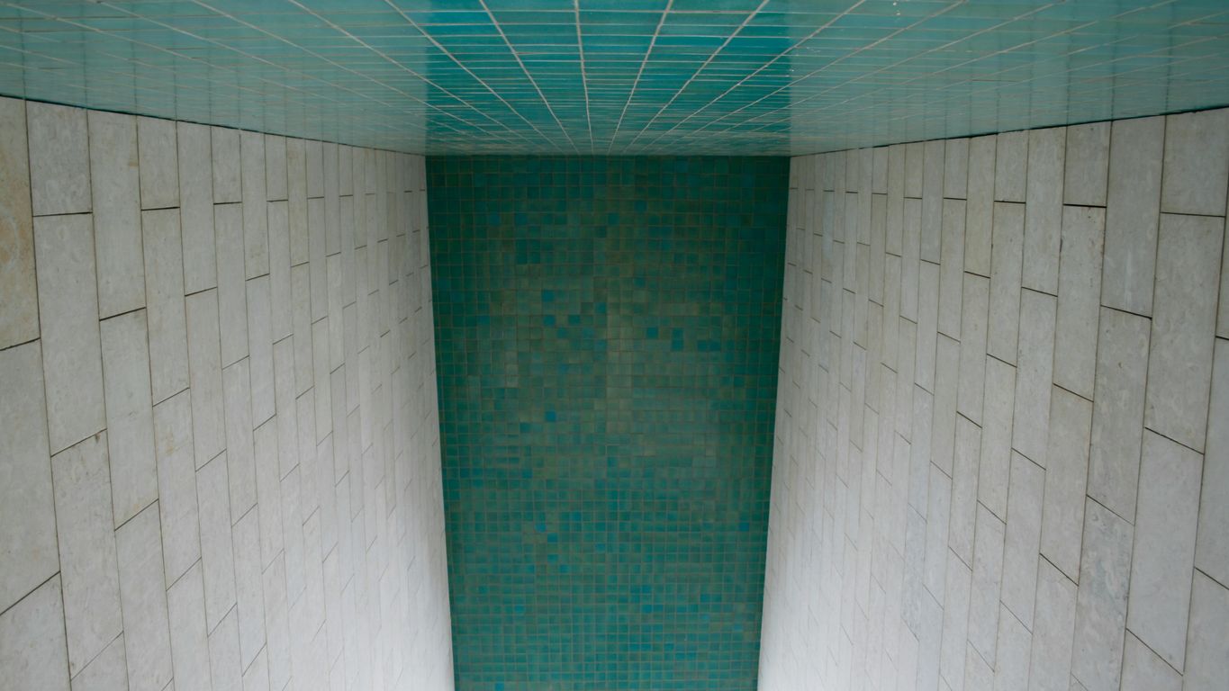 a white toilet sitting in a bathroom next to a tiled wall