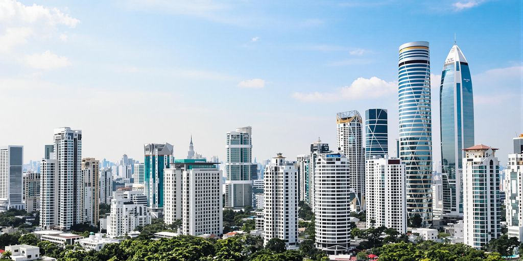 Bangkok skyline with luxury condos and greenery.