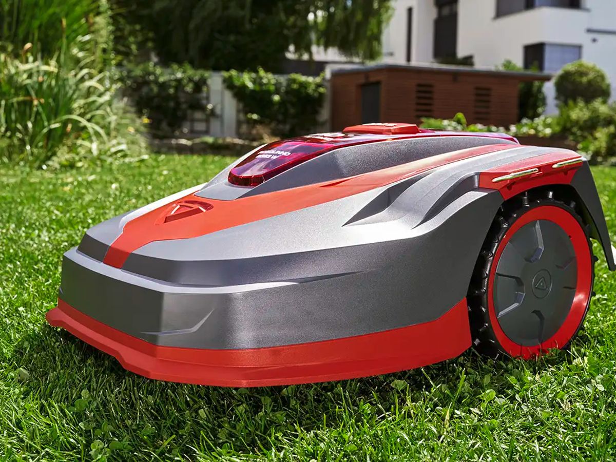 A robotic lawn mower on green grass in a garden.