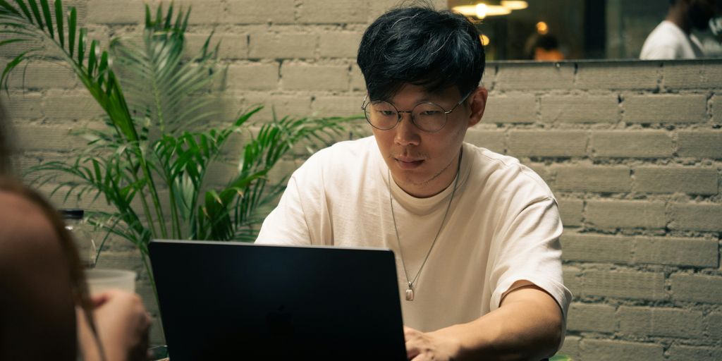 Man works on a laptop at a cafe.