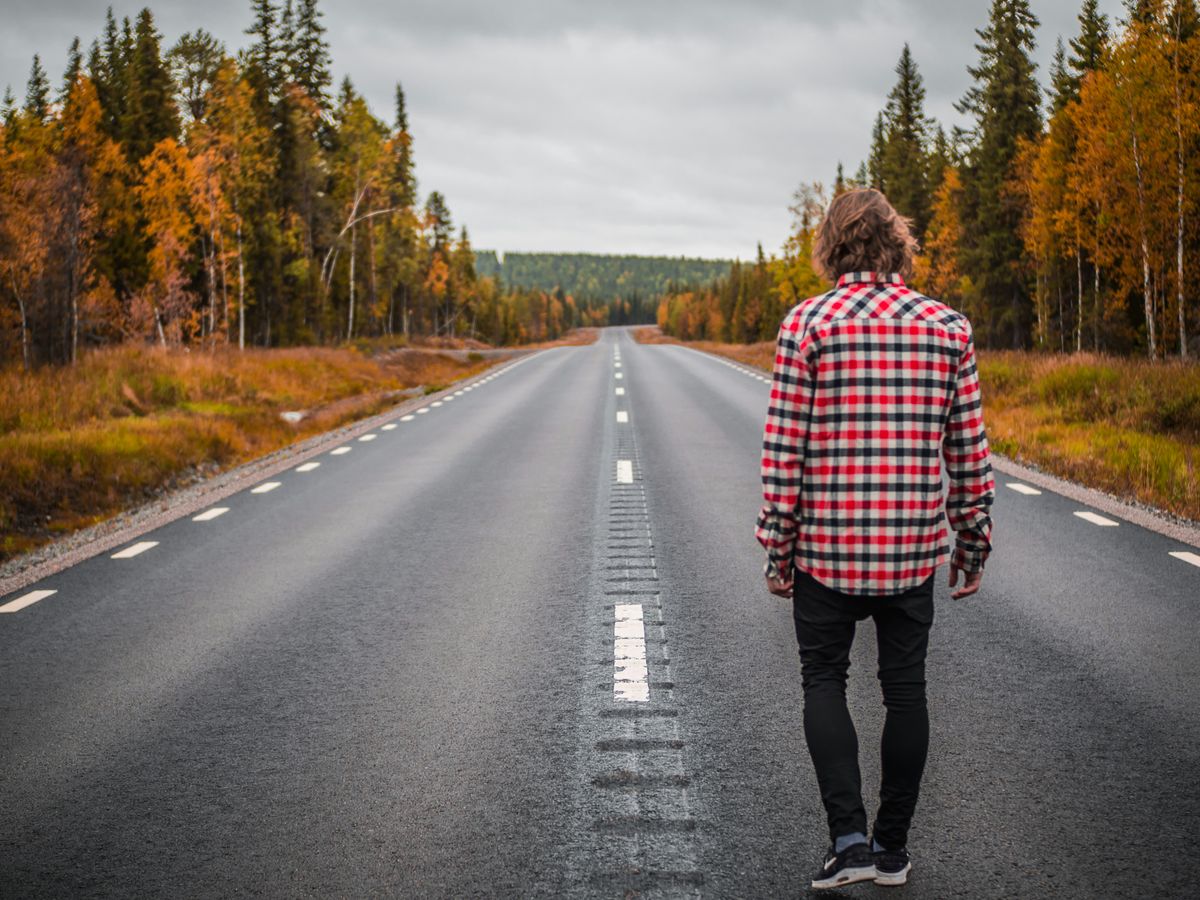 person standing on middle of blacktop road during daytime