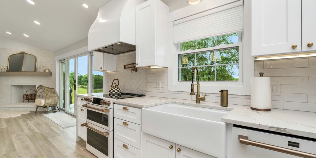 a kitchen with white cabinets and a large window