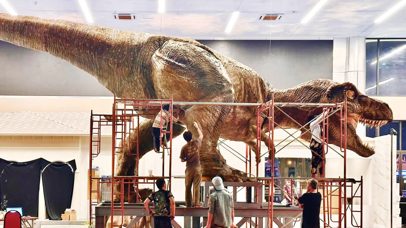 Life-sized dinosaur model being constructed in a large space.