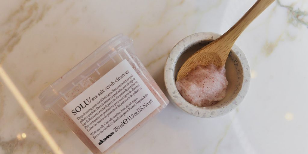 Cosmetic product and facial cleanser with brush on marble background.