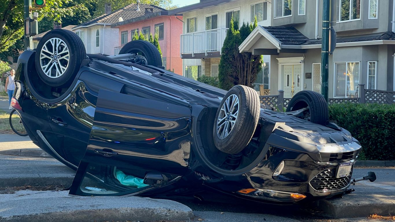 A car overturned on its side on a street.