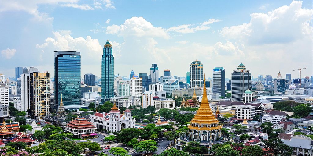 Bangkok skyline with skyscrapers and lush greenery.
