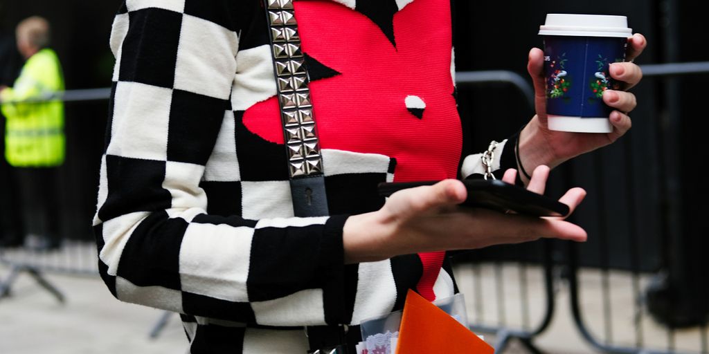 woman holding disposable cup and smartphone