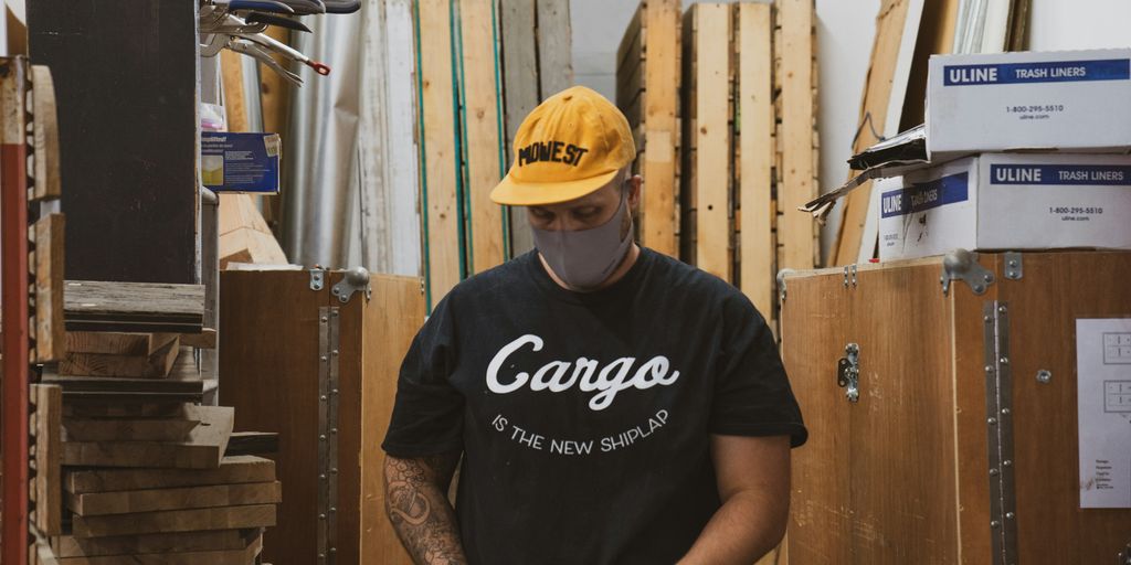 man in black crew neck t-shirt and yellow cap holding black smartphone