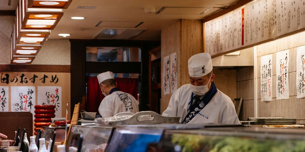 Sushi chefs preparing food in a japanese restaurant.