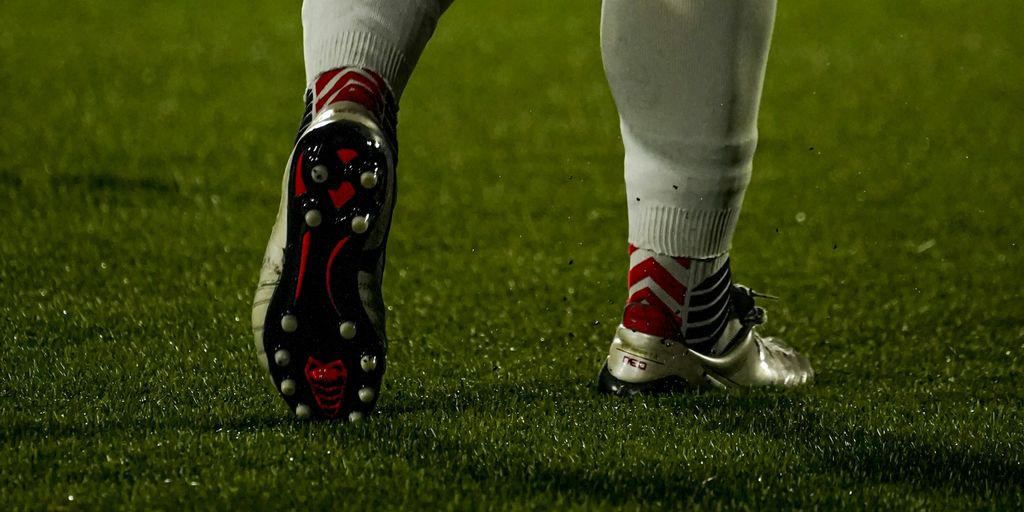 Football player's legs and cleats on the grass.